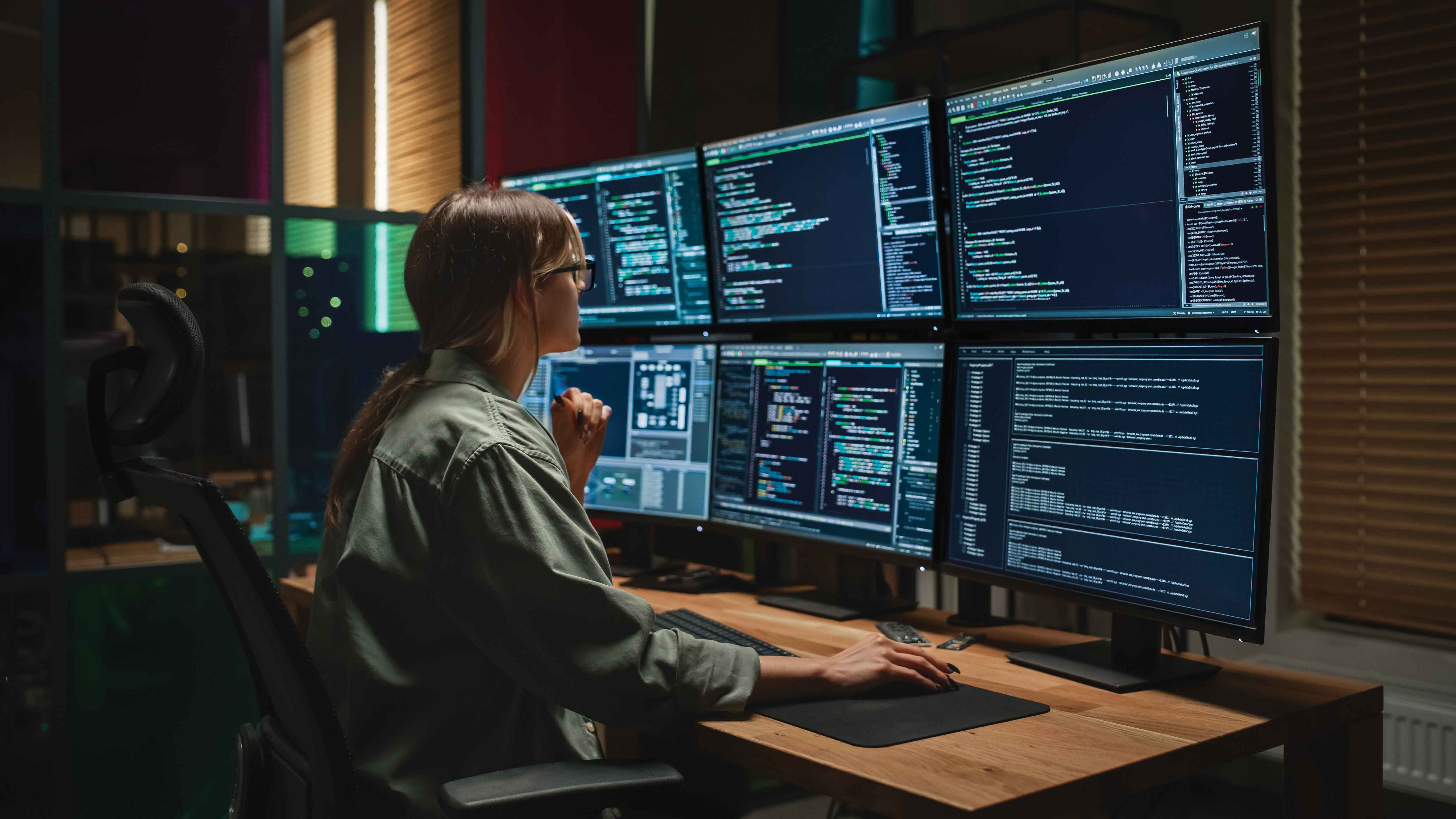 Picture of woman looking at multiple screens indicating cybersecurity